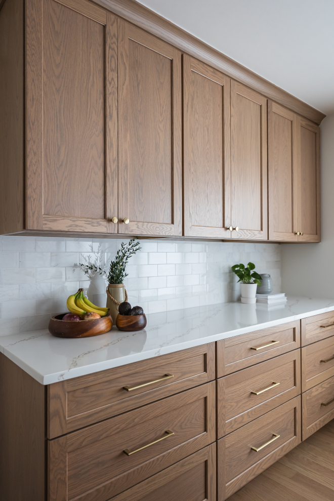 Shaker-Style-White-Oak-Cabinets-Kitchen-Storage Upper and lower shaker-style white oak cabinets stained in Minwax Weathered Oak with brass hardware, marble backsplash, and quartz countertops, paired with Benjamin Moore White Dove walls in a bright kitchen remodel