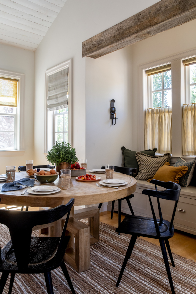 Breakfast area featuring chunky walnut round table, black solid wood chairs, and striped jute rug, adding rustic French Country style