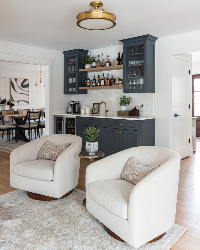 Sitting-Wet-Bar-Area Neutral swivel chairs and soft rug in sitting area overlooking wet bar with Benjamin Moore Westcott Navy cabinets, quartz countertop, and Minwax Weathered Oak accents