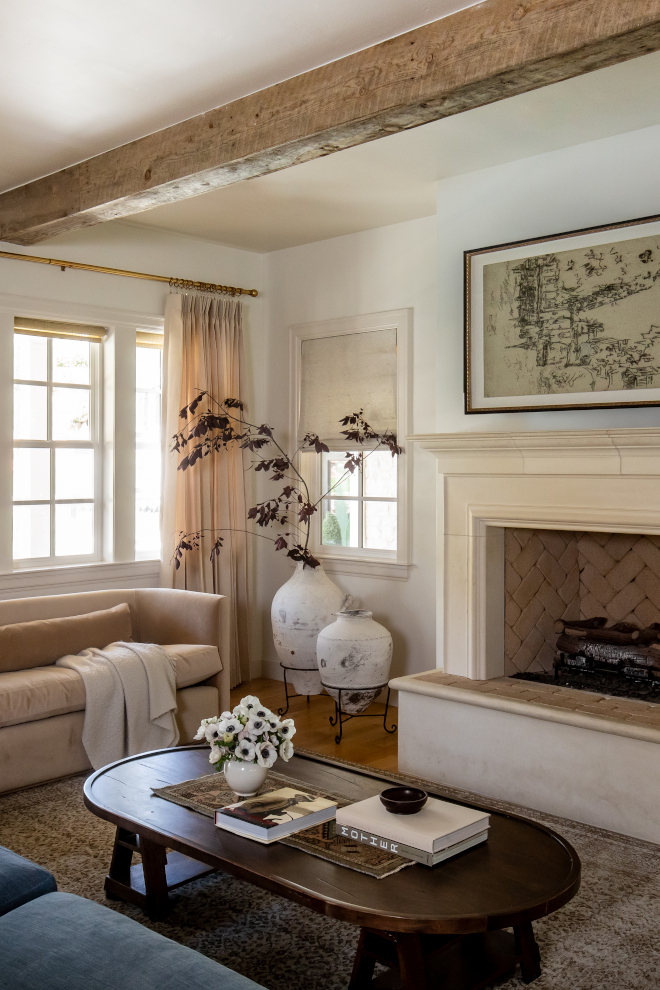Family room with curved velvet sofa, Swiss Coffee by Benjamin Moore painted walls, and linen draperies with brass hardware in a French Country mountain home.