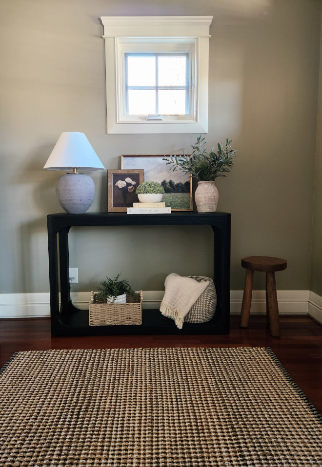 how-to-style-a-console-tale-ideas Styled entryway console table with a muted tone lamp, framed artwork, stacked books, and a terracotta vase with olive branches.