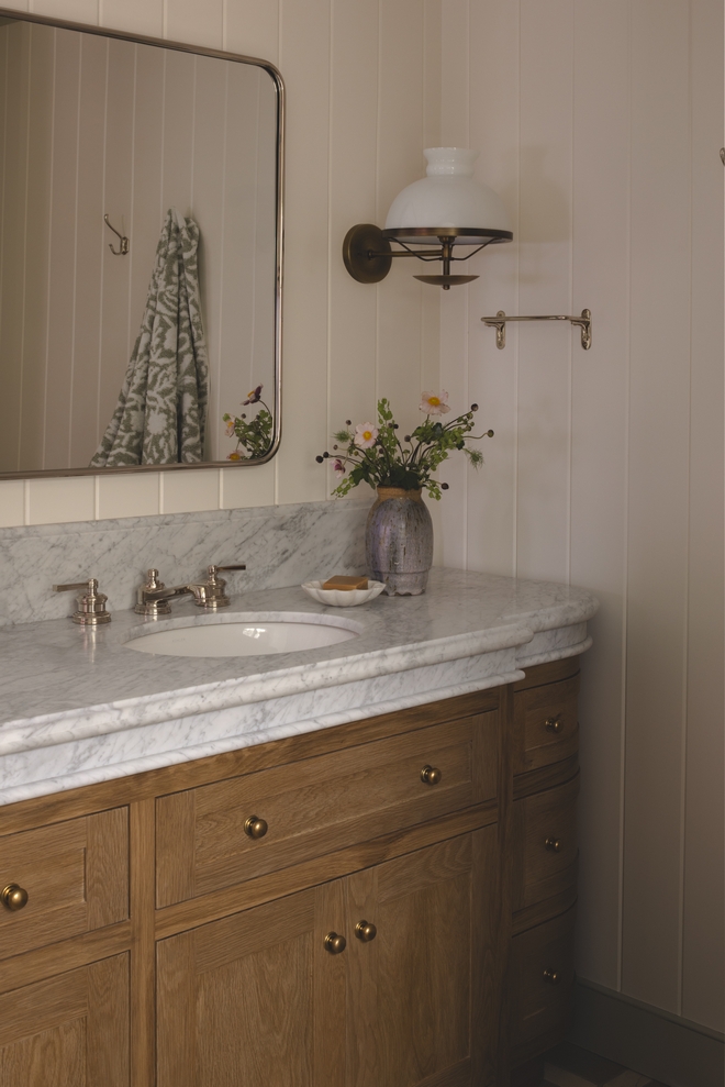 Carrara marble countertop with ornate edge and brass hardware