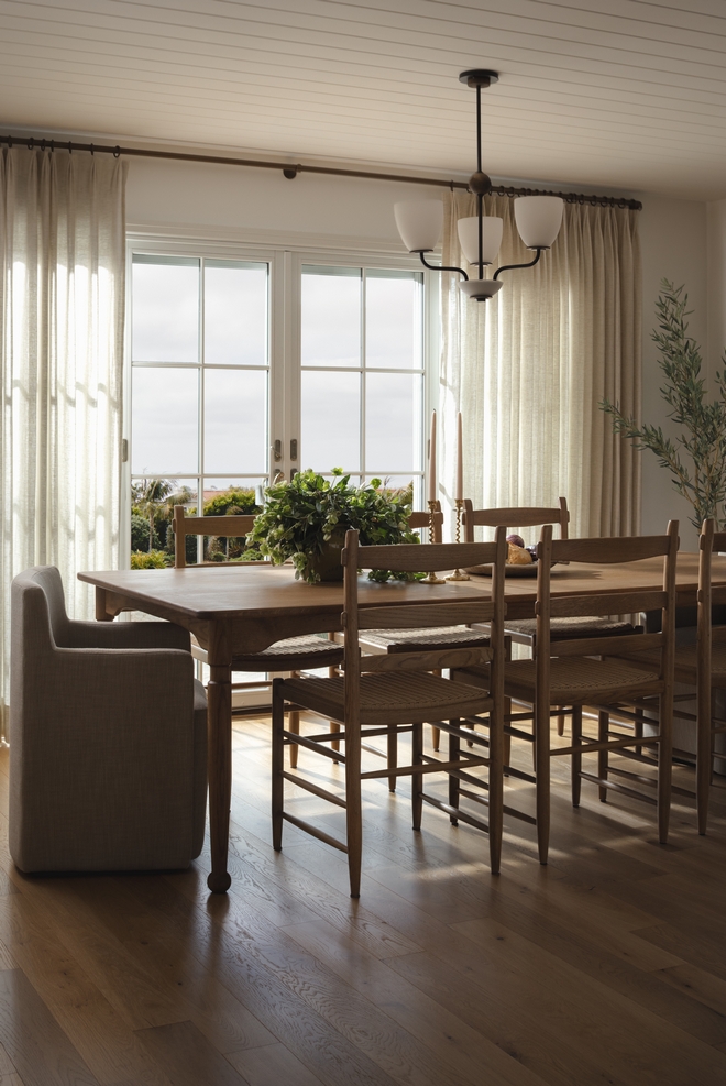 coastal dining room with oak dining table linen curtains wood floors and patio doors bringing in natural light