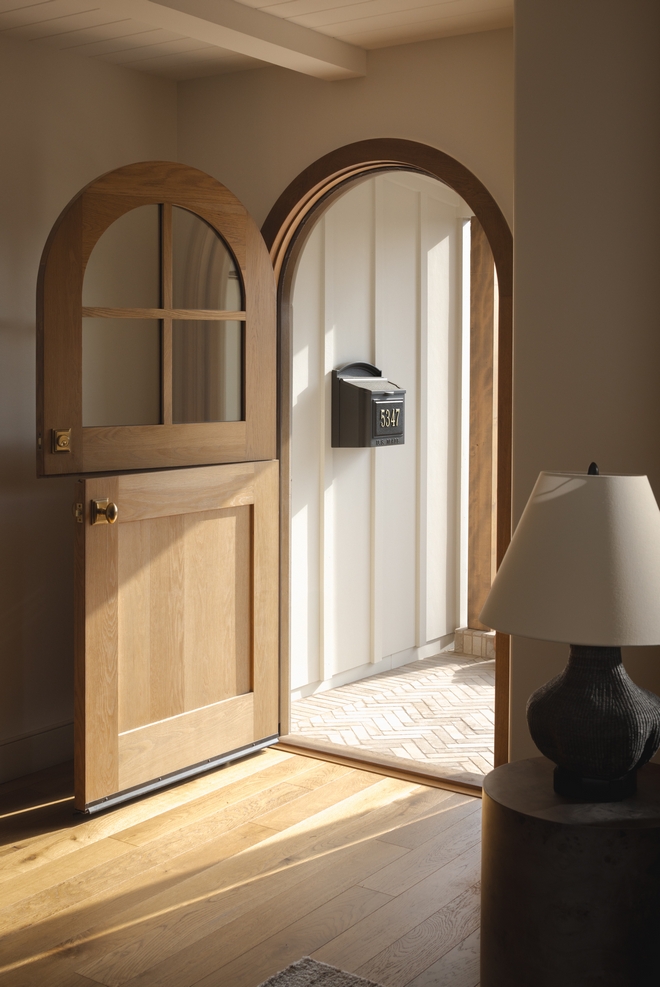 entry foyer with open white oak Dutch door sunlight streaming in and wide plank white oak floors in warm coastal cottage interior