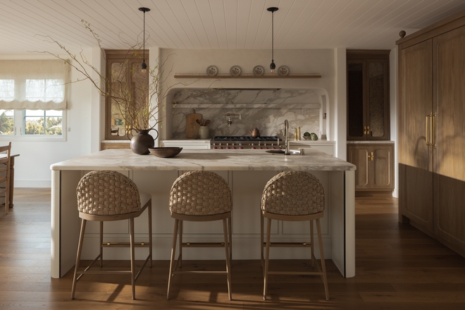 kitchen with Benjamin Moore Ballet White cabinets white oak cabinetry antique mirror cabinet doors marble slab backsplash and range alcove