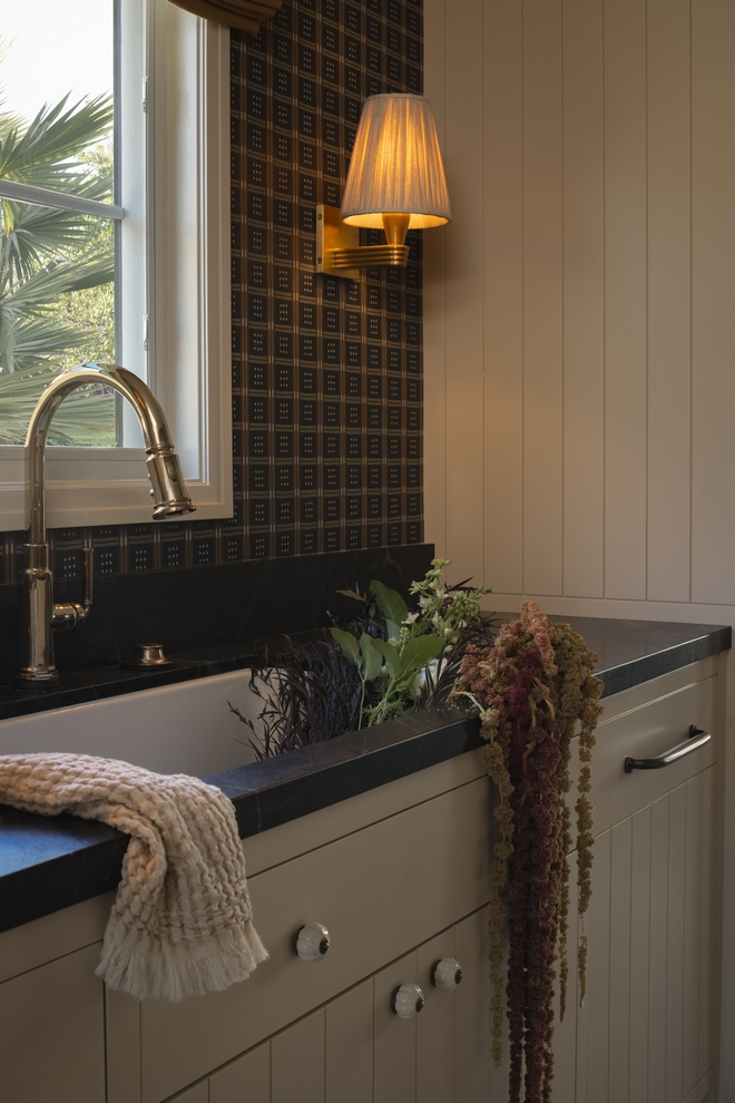 scullery sink under window with dark wallpaper and soapstone countertops