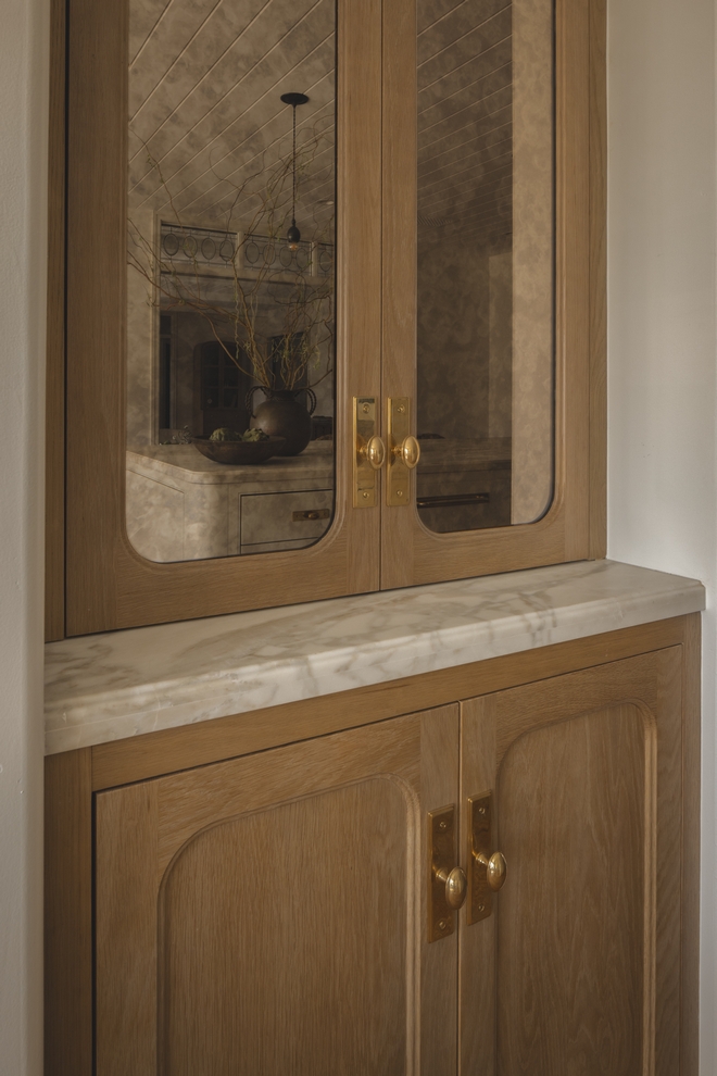 white oak kitchen cabinets with antique mirror inset doors flanking range alcove in neutral kitchen