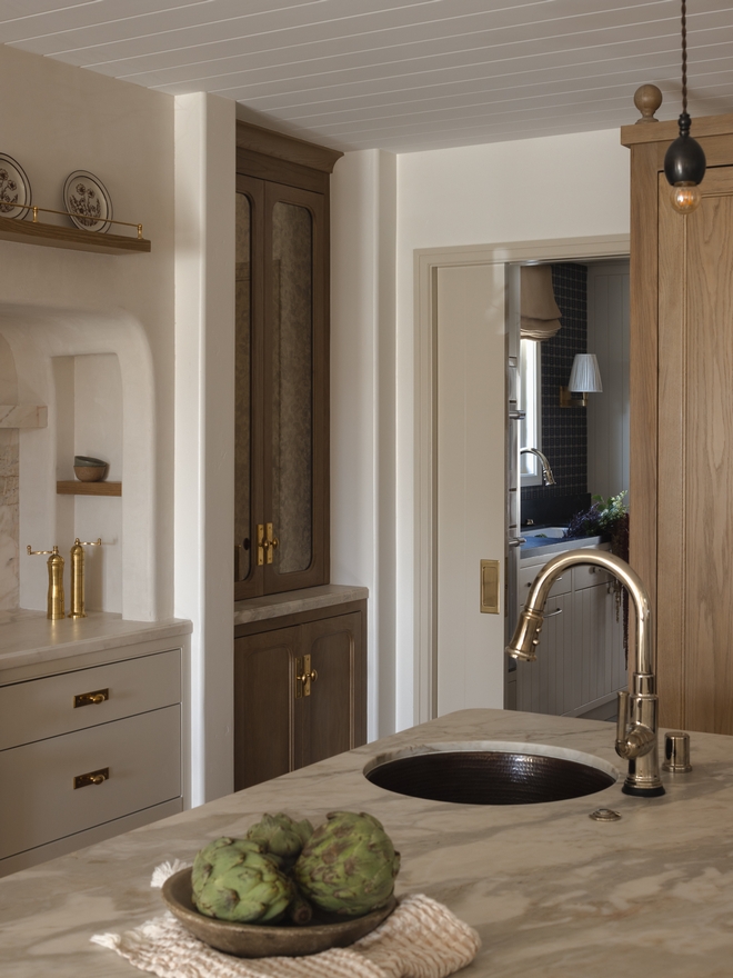 round hammered metal kitchen sink with modern pull down faucet in warm neutral kitchen