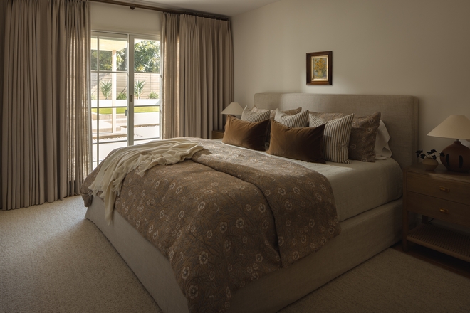 primary bedroom with linen slipcovered bed neutral rug and layered bedding