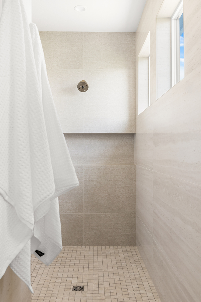 Walk-in shower with neutral large wall tiles and safe pan tiles in Idaho home