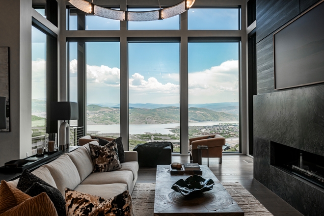 modern living room with fireplace and full-height windows overlooking valley