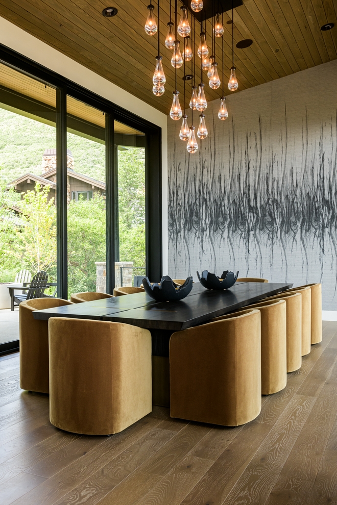 dining room with wood table, warm upholstered chairs and modern pendant lighting