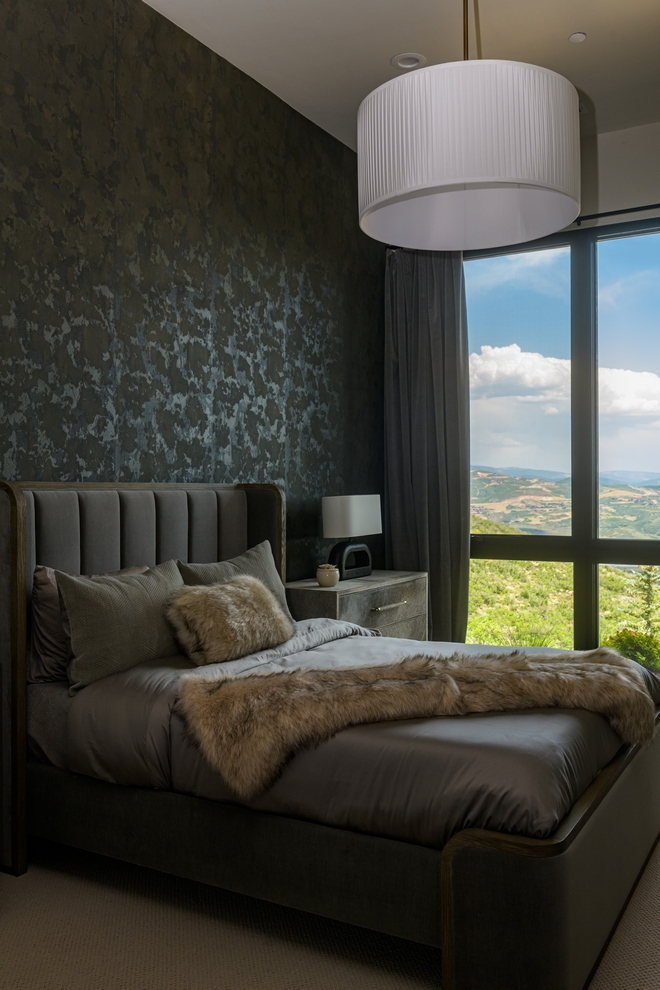 bedroom with dark textured walls, soft bedding and large window view