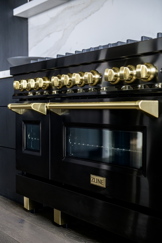 close-up of luxury kitchen range with brass knobs and black finish