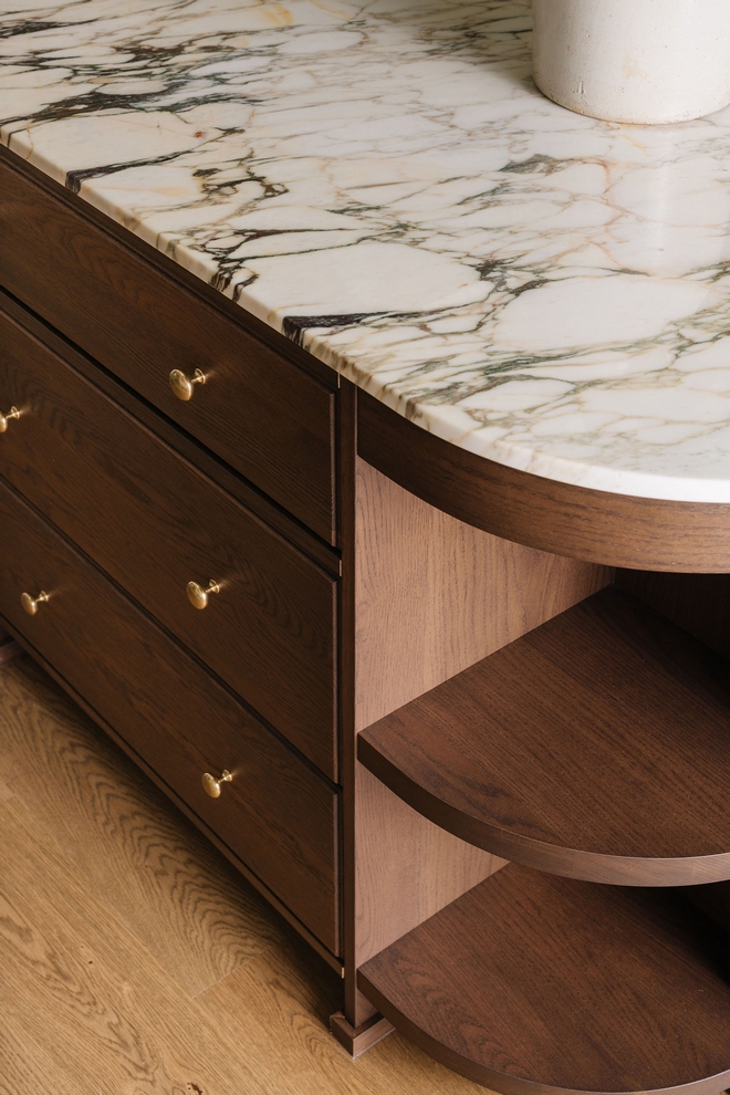 Dark Wood Kitchen Island with Marble Countertop and Curved Shelving Detail Dark Wood Kitchen Island with Marble Countertop and Curved Shelving Detail #DarkWoodKitchenIsland #KitchenIsland #MarbleCountertop #CurvedShelvingDetail #Curvedisland