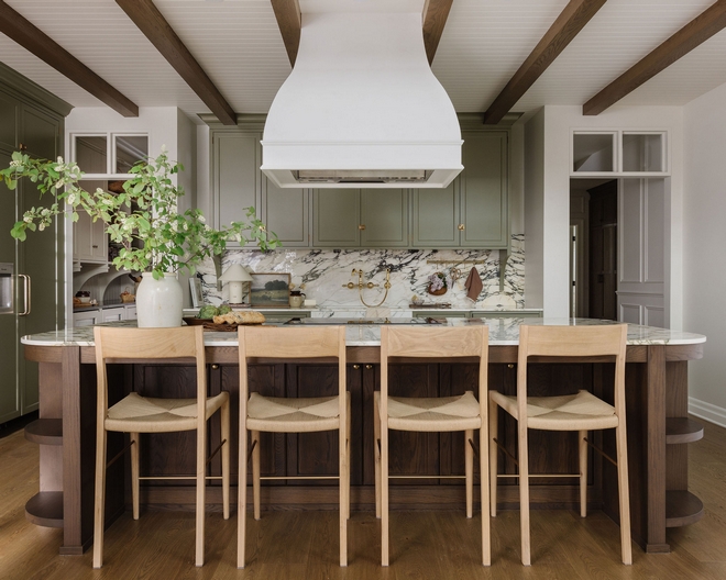 Elegant classic kitchen featuring Benjamin Moore Louisburg Green cabinetry, Calacatta Viola marble countertops and backsplash, wood island with seating, and exposed wood beam ceiling.