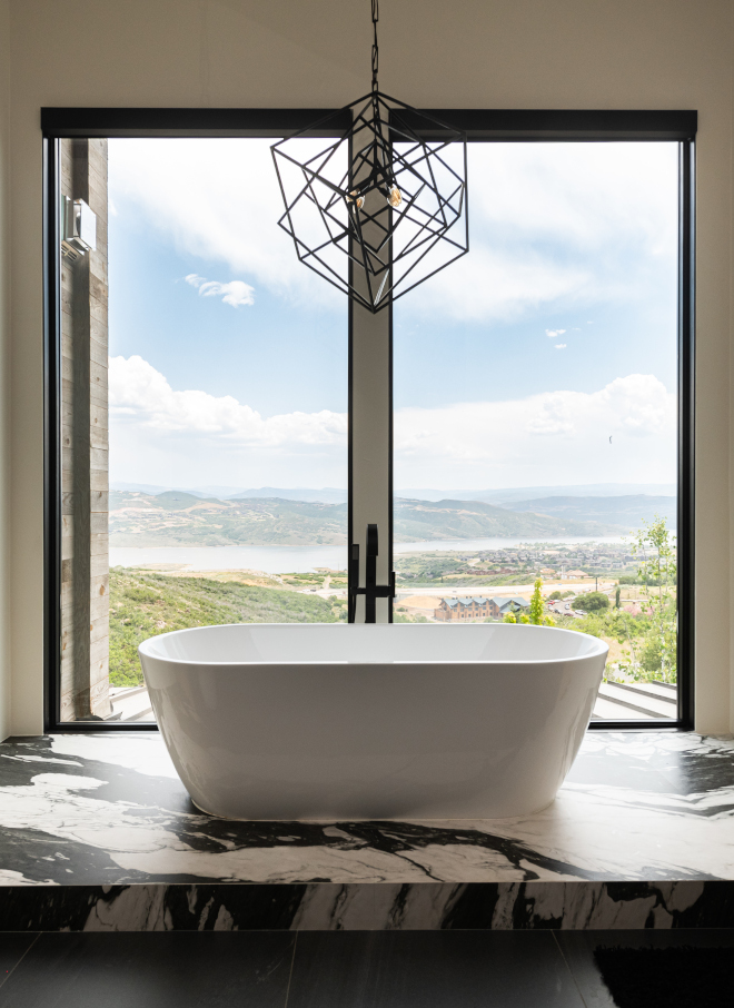 reestanding bathtub centered in front of large window with scenic mountain views