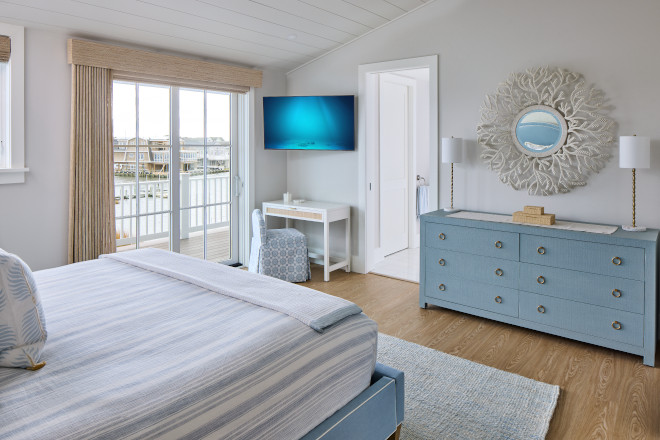 Coastal primary bedroom with Benjamin Moore Santorini Blue dresser, woven shades, and soft gray walls