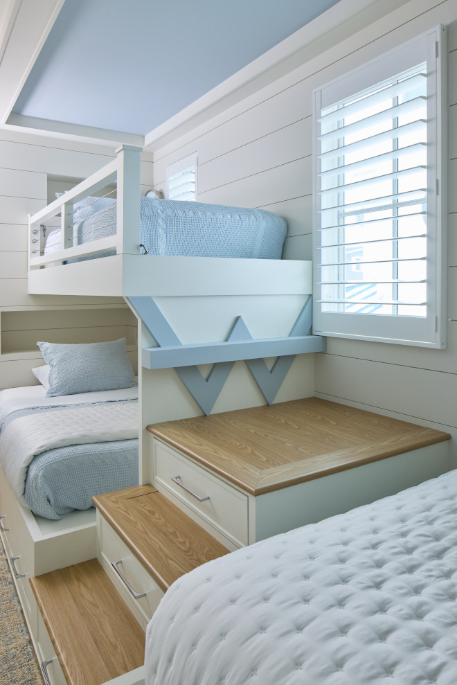 Coastal bunk bedroom with white built-in bunk beds, blue tray ceiling, and shiplap walls