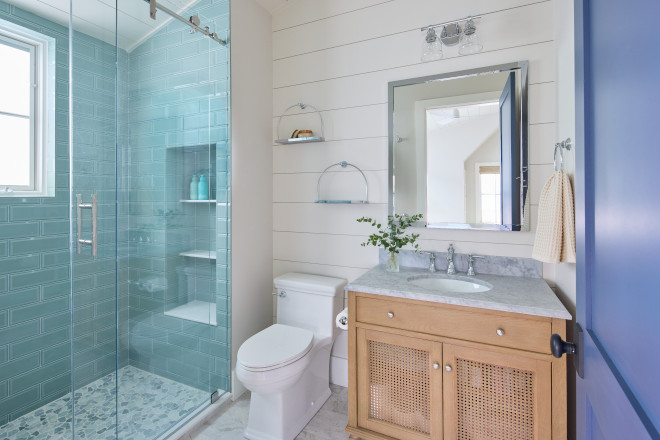 Coastal guest bathroom with white shiplap walls, blue subway tile shower, and natural wood vanity