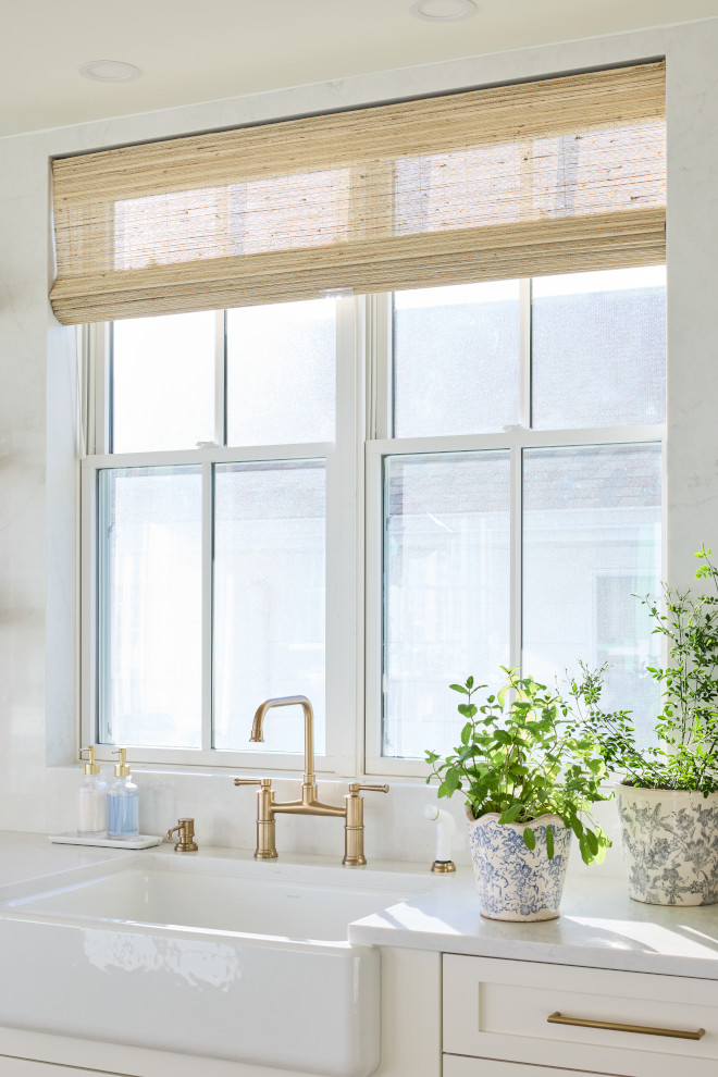 Coastal kitchen with woven roman shades, white quartz counters, and blue-and-white planters
