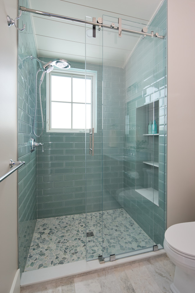Coastal shower with soft blue subway tile, flagstone mosaic floor, and glass enclosure