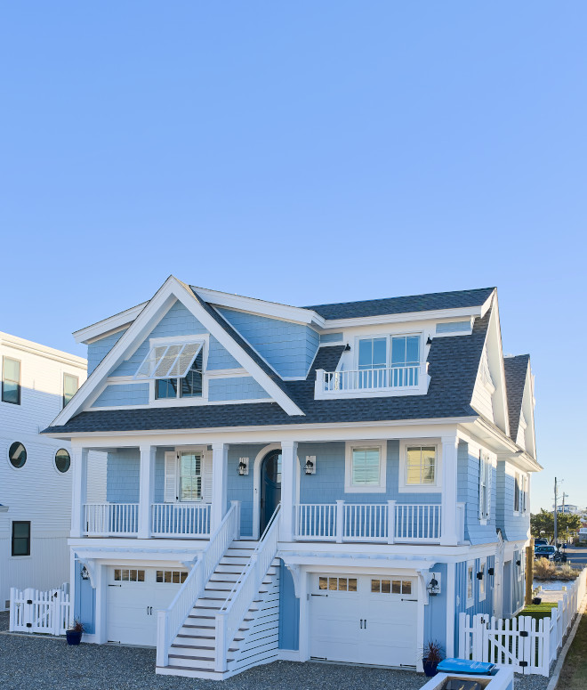Blue coastal beach house with white trim, waterfront decks, outdoor lounge spaces, and rooftop terrace overlooking the bay.