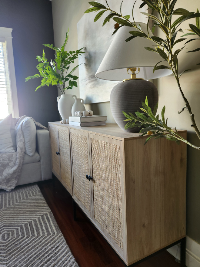 Earthy toned organic modern living room with neutral furniture, oversized artwork, textured pillows, olive trees, and layered decor creating a warm designer-inspired space.