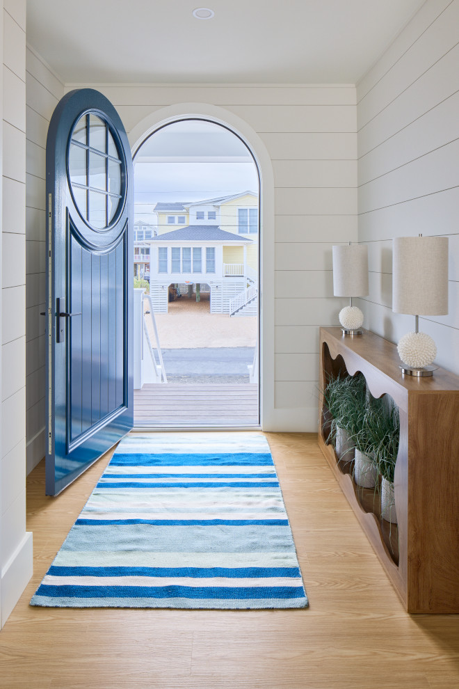 Beach house entry with blue door, striped rug, wood console, and neutral decor