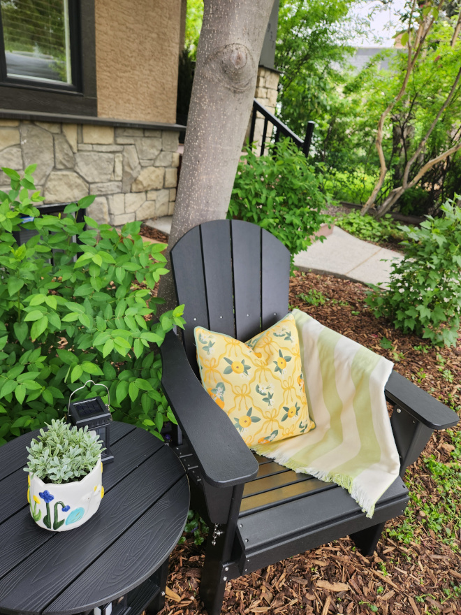 Comfortable Adirondack chairs styled with colorful outdoor accessories and fresh flowers beside a small outdoor side table.