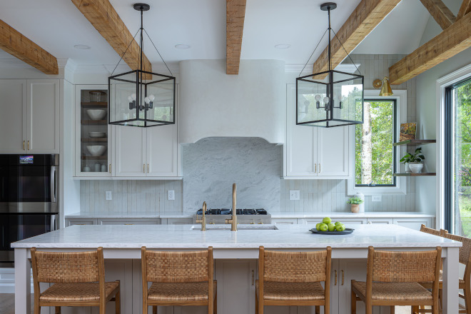 benjamin-moore-steam-gray-owl-kitchen-brass-faucet Kitchen featuring Benjamin Moore Steam upper cabinets, Benjamin Moore Gray Owl lower cabinets and island, a warm brass bridge faucet, plaster range hood, and rustic wood ceiling beams.