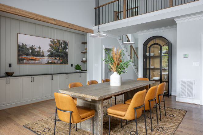 dining-room-custom-built-ins-vertical-paneling Dining room with custom built-in cabinetry, vertical paneling, warm leather dining chairs, wood table, pendant lighting, and Sherwin Williams Reserved White walls.