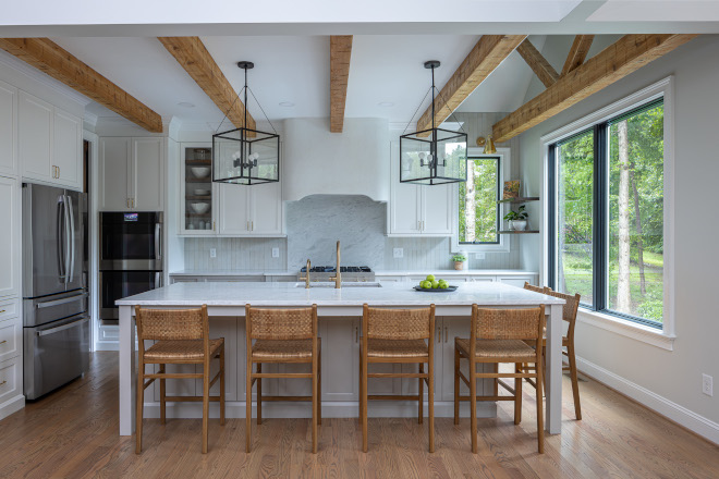 the-perfect-benjamin-moore-kitchen-color-combination Kitchen featuring Benjamin Moore Steam upper cabinets, Benjamin Moore Gray Owl lower cabinets, wood beams, woven stools, and a large island.