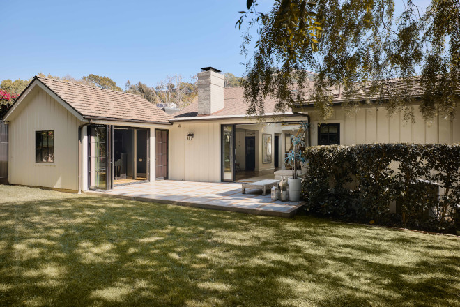 hollywood-hills-backyard-california-indoor-outdoor-living Backyard of a Hollywood Hills home featuring a spacious patio, sliding glass doors, lush lawn, and seamless indoor-outdoor living.