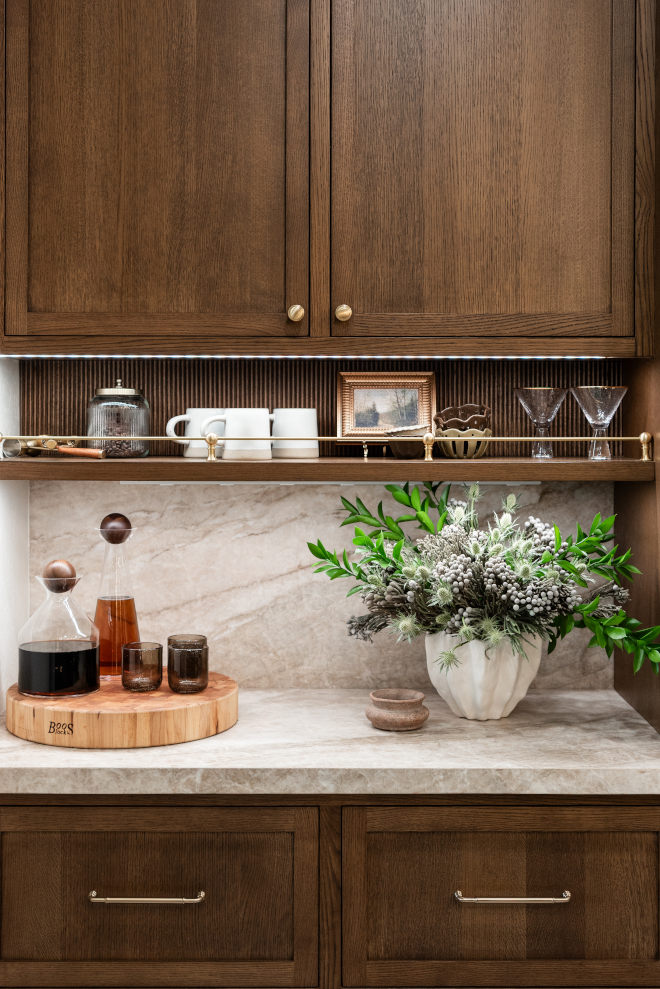 brass-rail-open-shelf-kitchen Open kitchen shelf with a brass rail displaying mugs, glassware and decorative accessories beneath custom cabinetry.