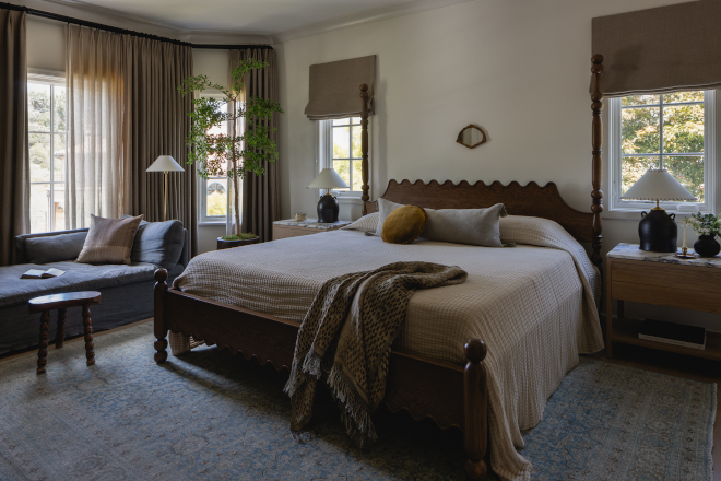 Earthy-Modern-English-Country-Bedroom Earthy Modern English Country bedroom with a carved dark wood bed, taupe window treatments, charcoal chaise and olive accent pillow.