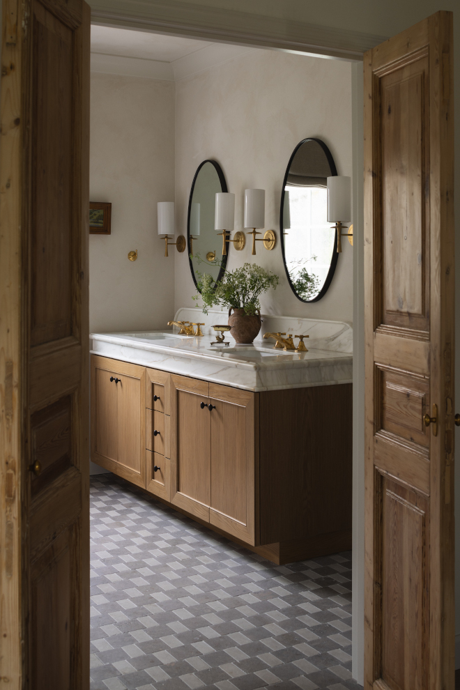 Modern-English-Country-Bathroom-with-Wood-Vanity Modern English Country bathroom featuring antique wood doors, a natural wood double vanity, marble countertop and checkered stone floor.