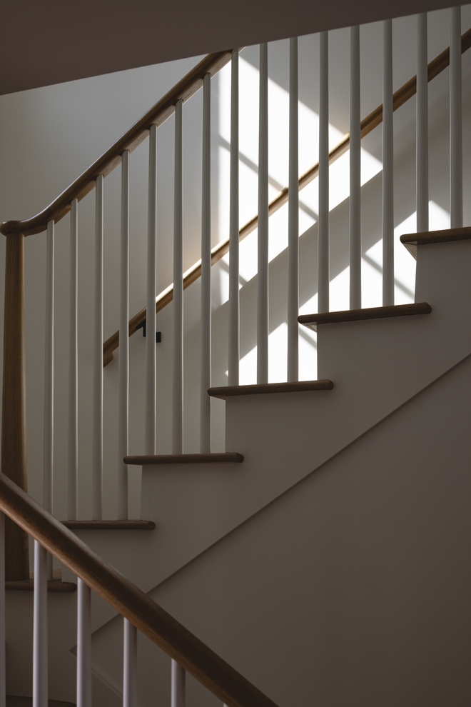 Timeless-Wood-and-White-Staircase Timeless staircase with natural wood treads and handrails, white risers, slim white spindles and warm sunlight.