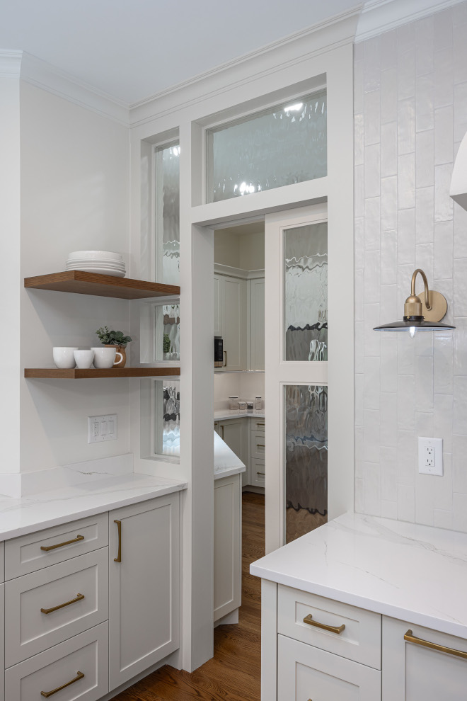 Kitchen Scullery with Textured Glass Pocket Door and White Cabinets White kitchen with a textured-glass pocket door in the open position, leading to a separate scullery with white cabinetry and stainless steel refrigerator.