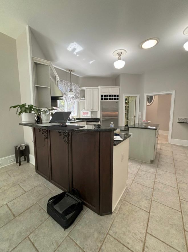 North Carolina Kitchen Before Renovation with Dark Granite Countertops Before the renovation, the kitchen featured dark granite countertops, a raised breakfast bar, and beige tile flooring. The original layout offered several work surfaces, but the different counter heights made the space feel visually busy.