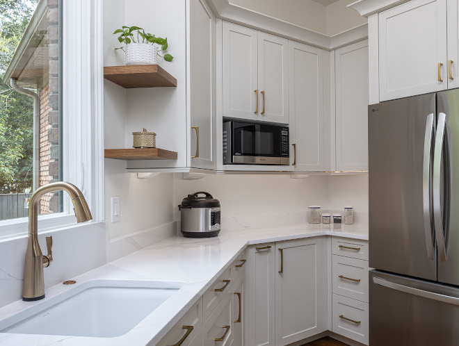 White Quartz Scullery Countertop with Brass Faucet and Wood Shelves Close-up of a small prep kitchen sink with brushed brass faucet, white quartz countertop and backsplash, white Shaker cabinets, and floating wood shelves.