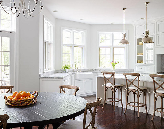 Kitchen. Gorgeous kitchen features Restoration Hardware Harmon Pendants illuminating a white center island topped with gray quartzite lined with three French x back counter stools. Kitchen bay window is filled with white cabinets paired with grey quartzite counters fitted with a farmhouse sink. #Kitchen Shophouse Design.