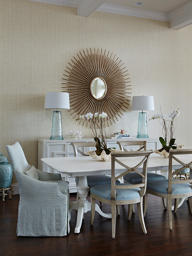 Dining Room. Coastal Dining Room. This chic dining room features Hickory White side chairs in a Romo textile, a Somerset Bay Home dining table and Duralee fabric dresses the Lee Industries head chair. Neutral coastal dining room with sunburst mirror, neutral grasscloth wallpaper and blue accents. #Diningroom #CoastalInteriors #CoastalDiningRoom #Sunburst #Mirror #Neutral #Interiors JMA Interior Design.
