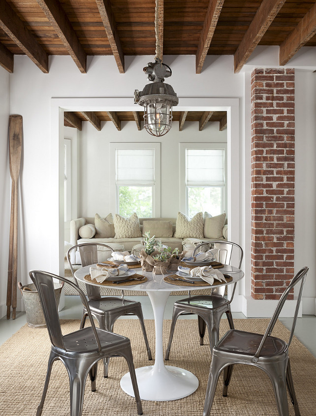 Dining Room. Transitional Dining Room. Cottage dining room. Cottage dining nook features rustic wood beams adorned with a vintage lantern over a Saarinen Dining Table surrounded by Tolix Chairs atop a jute rug.