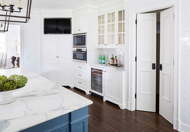 Kitchen Butler's Pantry and Bar Cabinet. Kitchen with butlers pantry and bar cabinet, floor-to-ceiling wall tile, pantry door, built-in ovens and built-in TV. The kitchen Countertop is Calcutta Gold Extra Marble. #Kitchen Martha O'Hara Interiors. 