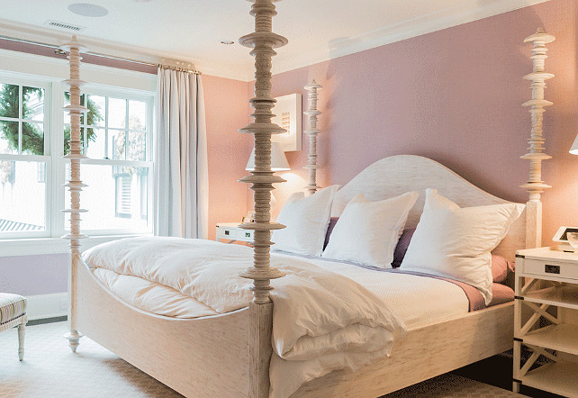 Lavender Bedroom. White and lavender bedroom features lavender walls framing a carved wood 4 poster bed dressed in white and lavender bedding flanked by white campaign nightstands with shelves accented with x trim atop gray geometric rug. #Lavender #Bedroom Brookes and Hill Custom Builders.