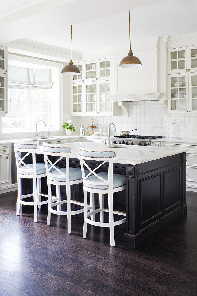 Medium Size Kitchen Layout. Two-tone L shaped kitchen with glass-front upper perimeter cabinets and white raised panel base perimeter cabinets paired with espresso stained kitchen island. Calcutta marble countertops paired with glossy white porcelain tile backsplash. #MediumKitchen #MediumSizedKitchen #KitchenLayout