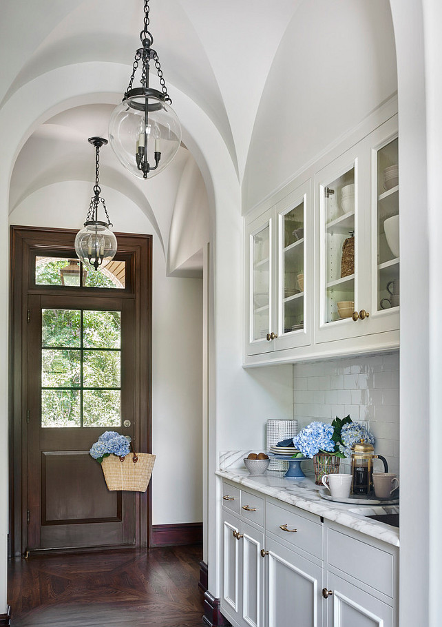 Butlers Pantry. Traditional Butlers Pantry. Traditional Butler Pantry Design. Stunning butler's pantry features a barrel ceiling dotted with Small Amphora Bell Jar Pendants illuminating glass front upper cabinets and white bottom cabinets paired with white marble countertops and a white glazed tiled backsplash laid out in a brick pattern. JackBilt Homes.