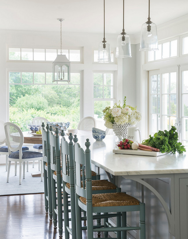 Gray Kitchen Island. Cottage kitchen features three glass pendants illuminating a gray kitchen island topped with white marble lined with turquoise blue counters tools with rush seats. #Kitchen #Gray #KitchenIsland Digs Design Company.