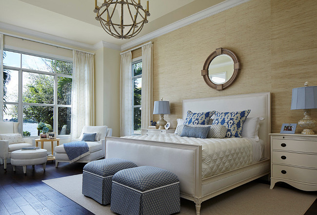 Master Bedroom. A bevy of furnishings in the master suite was acquired through Designers Buying Group: the Pearson bed and chaise, Somerset Bay Home bedside tables, Hickory White ottomans, and a Visual Comfort chandelier. A Kravet wallcovering and a mirror by Global Views lend a neutral backdrop; Raoul Textiles’ shams and a Duralee print on the ottomans bestow shades of blue. #MasterBedroom